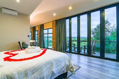 a bedroom with a bed and a large window at Cliffhanger Lodge in Mabula