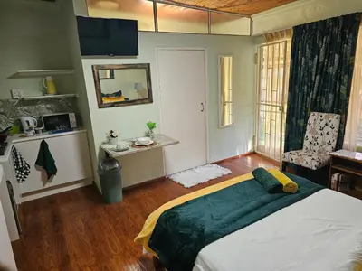 a bedroom with a large bed with a green blanket at King Sanctuary in Centurion