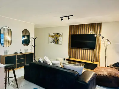 a living room with a couch and a flat screen tv at The Blyde Lagoon Apartment in Pretoria