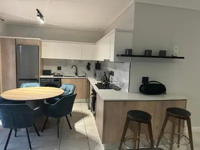a kitchen with a table and some chairs and a counter at The Blyde Lagoon Apartment in Pretoria