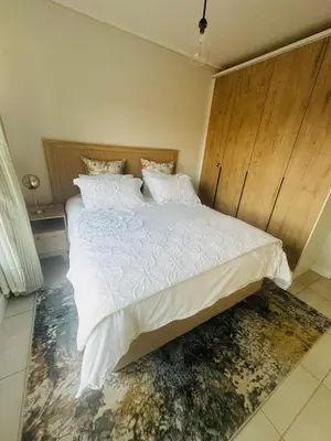 a bedroom with a large bed with white sheets and pillows at The Blyde Lagoon Apartment in Pretoria