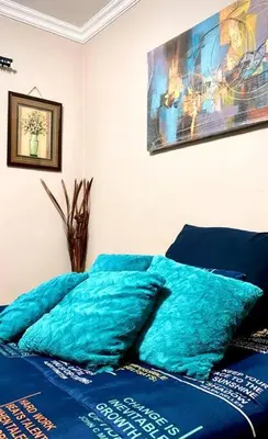 a bed with blue sheets and a painting on the wall at SummerPlace - Studio Apartment with Kitchenette in Modimolle