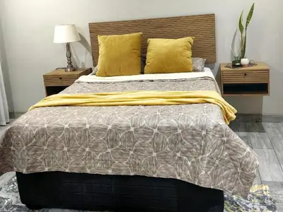 a bedroom with a large bed with yellow pillows at SuLo Guesthome in Phalaborwa