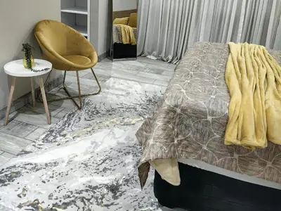 a bedroom with a bed and a chair and a rug at SuLo Guesthome in Phalaborwa