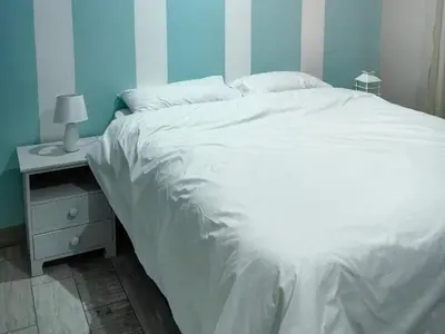 a bedroom with a white bed and a night stand at SuLo Guesthome in Phalaborwa