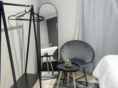 a room with a chair and a mirror and a bed at SuLo Guesthome in Phalaborwa