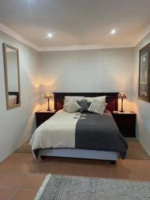 a bedroom with a large bed with two nightstands and a mirror at Pringle Studio in Benoni