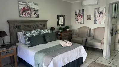 a bedroom with a large bed and a chair at Lumis Rest in Tzaneen