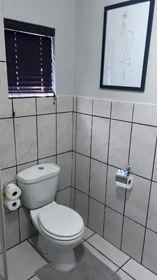 a bathroom with a toilet and a picture on the wall at Lumis Rest in Tzaneen