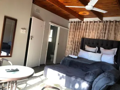 a bedroom with a bed and a table and a ceiling at Esibayeni Guesthouse in Nelspruit
