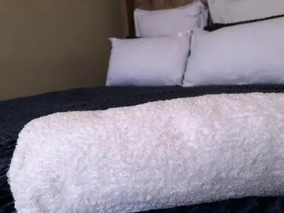 a bed with white sheets and pillows at Esibayeni Guesthouse in Nelspruit