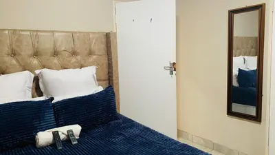 a bedroom with a bed with blue pillows and a mirror at Esibayeni Guesthouse in Nelspruit