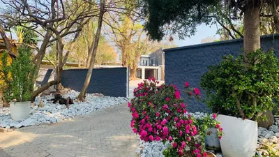 a garden with pink flowers in front of a building at Esibayeni Guesthouse in Nelspruit