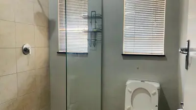 a bathroom with a toilet and a glass shower at Esibayeni Guesthouse in Nelspruit