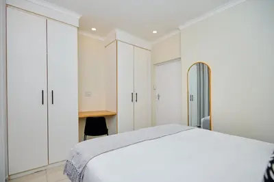 a white bedroom with a bed and white cabinets at The Dream, Unit N105 at Glen Park in Pretoria