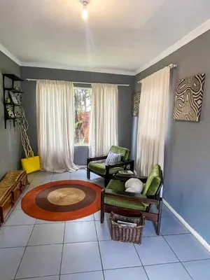 a living room with two chairs and a rug at Serenity in the city - one bedroom apartment in Pretoria