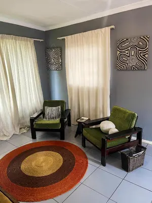 a living room with two chairs and a rug at Serenity in the city - one bedroom apartment in Pretoria