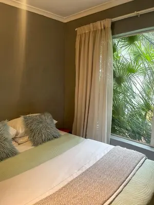 a bed with two pillows sitting next to a window at Serenity in the city - one bedroom apartment in Pretoria