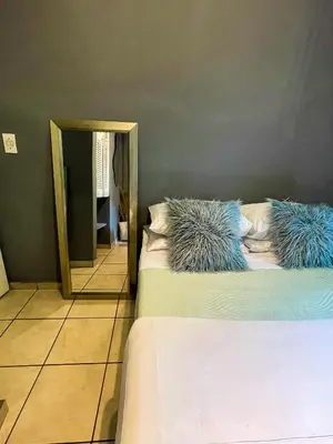 a bedroom with two beds with pillows and a mirror at Serenity in the city - one bedroom apartment in Pretoria