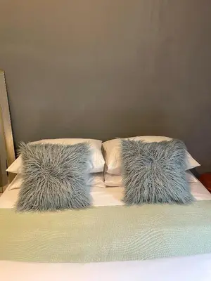 a bed with two pillows with furry pillows on it at Serenity in the city - one bedroom apartment in Pretoria