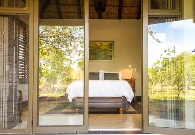 a bedroom with a bed and sliding glass doors at Mokaikai - The Great Buffalo in Mabula
