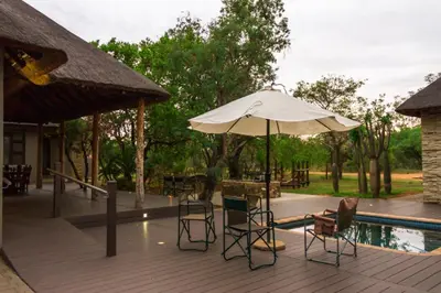 a patio with chairs and an umbrella next to a pool at Mokaikai - The Great Buffalo in Mabula
