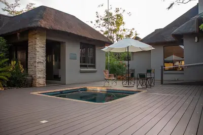 a deck with a pool and a house with an umbrella at Mokaikai - The Great Buffalo in Mabula