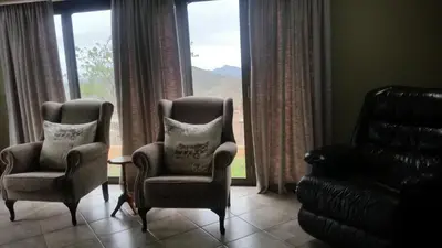 a living room with two chairs and a couch and a window at Jackal Buzzard Mountain Haven in Hillsowen