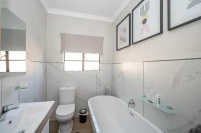 a white bathroom with a tub and a toilet and a sink at Golden Utopia in Nelspruit