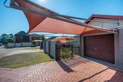 a building with an open gate with an umbrella at Golden Utopia in Nelspruit