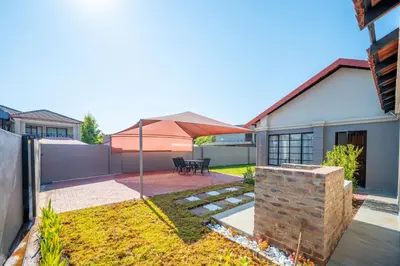 a backyard with a patio with a table and umbrella at Golden Utopia in Nelspruit