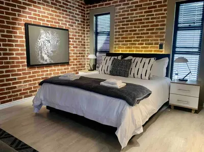 a bedroom with a large bed and a brick wall at Menlyn View Unit 8 in Pretoria