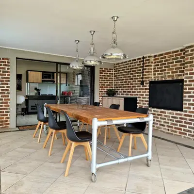 a dining room table with chairs and a brick wall at Menlyn View Unit 8 in Pretoria