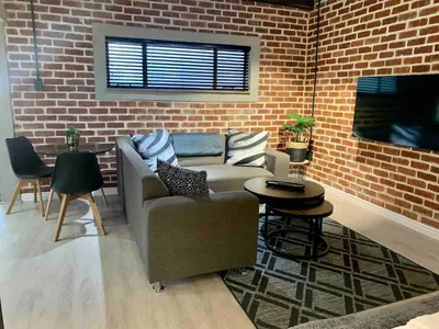 a living room with a couch and a brick wall at Menlyn View Unit 8 in Pretoria