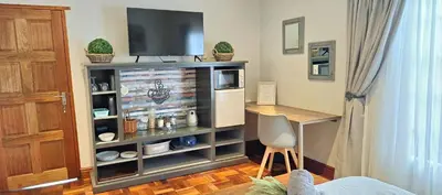 a room with a entertainment center with a tv and a desk at Stay at Fairway in Centurion