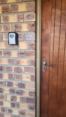 a clock on a brick wall next to a door at Lloyds - 9 in Ermelo