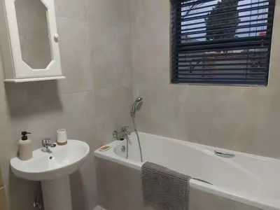 a bathroom with a sink and a bath tub and a sink at Lloyds - 9 in Ermelo