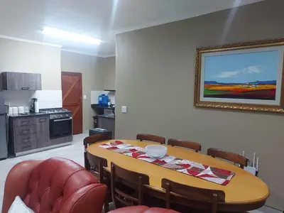 a dining room with a table and a kitchen at Lloyds - 9 in Ermelo