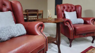 a living room with two leather chairs and a table at Lloyds - 9 in Ermelo