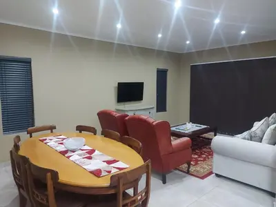a living room with a table and chairs and a tv at Lloyds - 9 in Ermelo