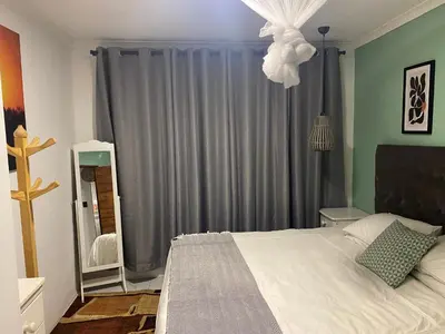 a bedroom with a bed and a window with gray drapes at Mamuka Africa II in Midrand
