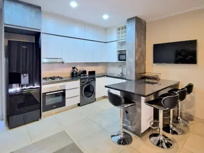 a kitchen with white cabinets and a black counter top at Menlyn View Unit 6 in Pretoria