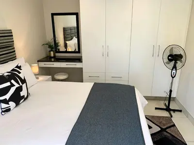 a bedroom with a bed with a fan and a mirror at Menlyn View Unit 6 in Pretoria