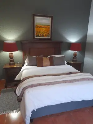 a bedroom with a large white bed with two lamps at Yellowwood Accommodation in Polokwane