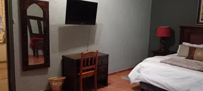 a bedroom with a bed and a television on the wall at Yellowwood Accommodation in Polokwane