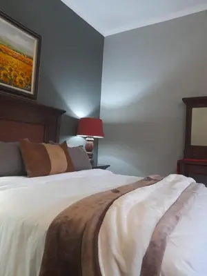 a bedroom with a bed with white sheets and brown pillows at Yellowwood Accommodation in Polokwane