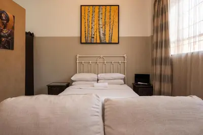 a bedroom with two beds and a painting on the wall at De Oude Hof Lodge in Delmas
