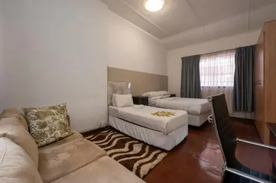 a living room with two beds and a couch at De Oude Hof Lodge in Delmas