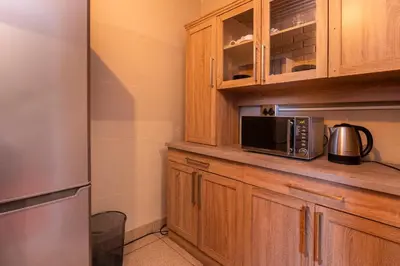 a kitchen with wooden cabinets and a microwave at De Oude Hof Lodge in Delmas