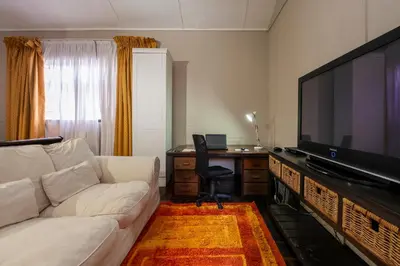 a living room with a white couch and a large television at De Oude Hof Lodge in Delmas